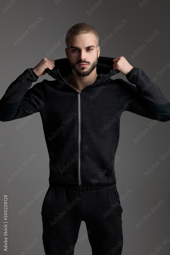 casual man wearing tracksuit standing and fixing his hood