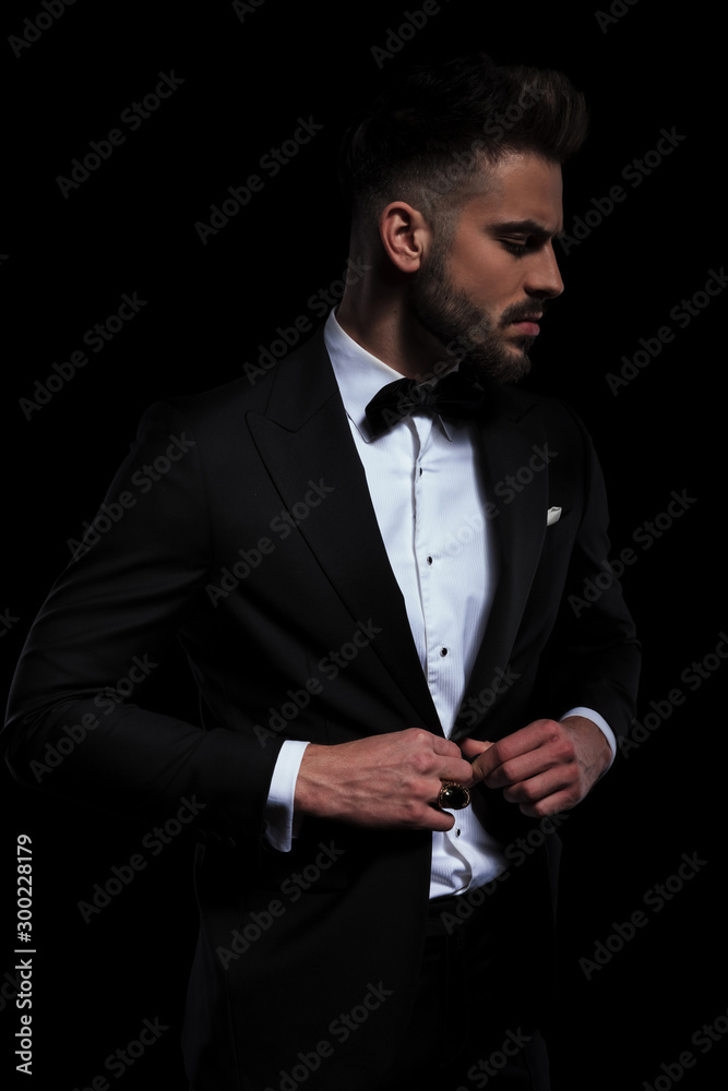 businessman wearing black tuxedo standing and fixing jacket businessman wearing black tuxedo standing and fixing jacket