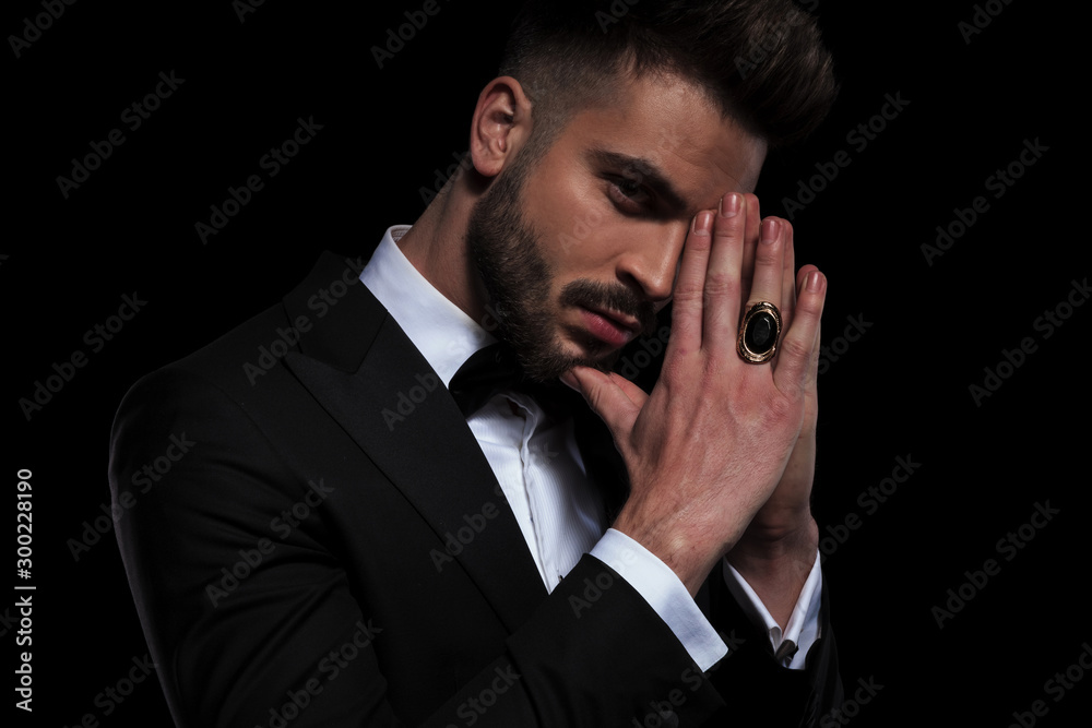 businessman wearing black tuxedo looking at camera with joined hands businessman wearing black tuxedo looking at camera with joined hands