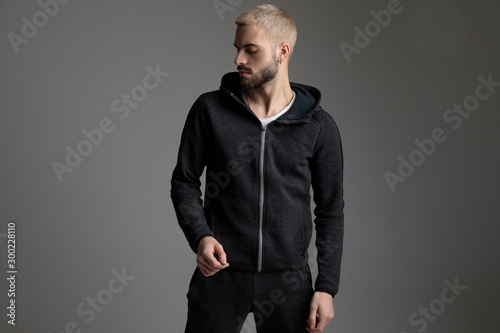 casual man wearing tracksuit standing and looking aside serious photo