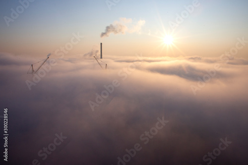 heavy fog over the city, purple sunny dawn over clouds, atmospheric smoke pollution concept