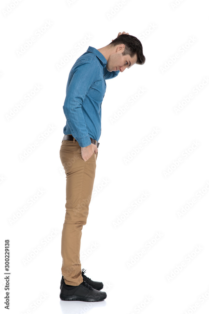 young smart casual man looking down and scratching head young smart casual man looking down and scratching head
