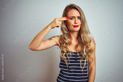 Young beautiful woman wearing stripes t-shirt standing over white isolated background Shooting and killing oneself pointing hand and fingers to head like gun  suicide gesture.