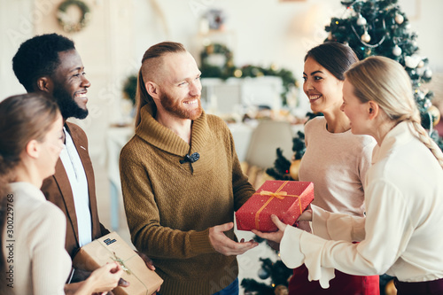 Photography Multi-ethnic group of cheerful young people exchanging gifts during Christmas pa