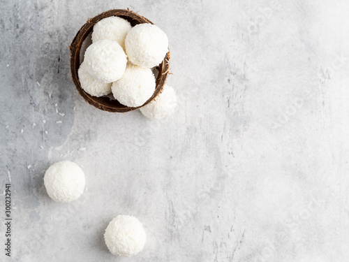 Coconut bliss balls in coconut shells on white gray background closeup view photo
