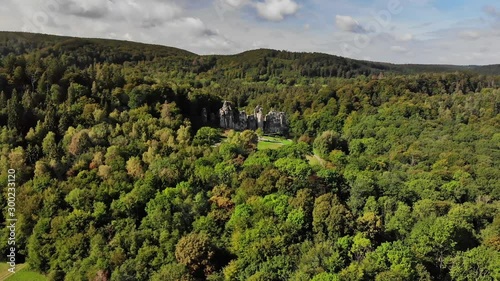 An aerial view of the famous sandstone rocks Externsteine in Germany. The autumn forest is already very colorful in September and sunlight shines on the rocks.