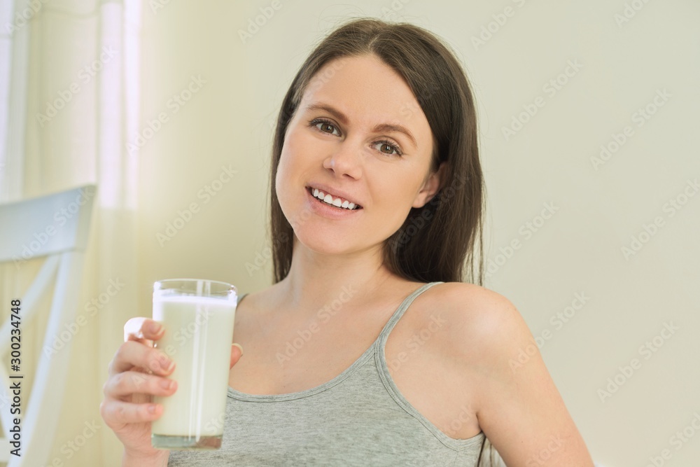 Young beautiful smiling woman drinking milk in glass Young beautiful smiling woman drinking milk in glass