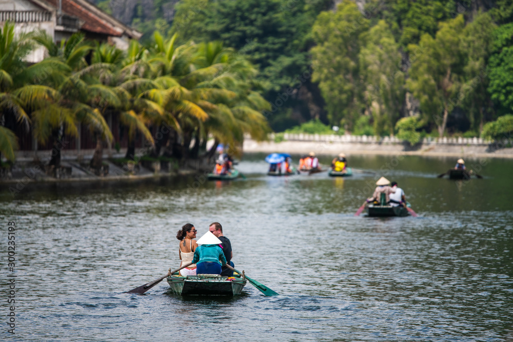 Vietnamese locals row rowing boats with their feet for tourists as they travel on a boat tour through the limestone caves of Ninh Binh Vietnamese locals row rowing boats with their feet for tourists as they travel on a boat tour through the limestone caves of Ninh Binh