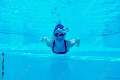 Young girl swimming underwater in the pool  female looking and smiling