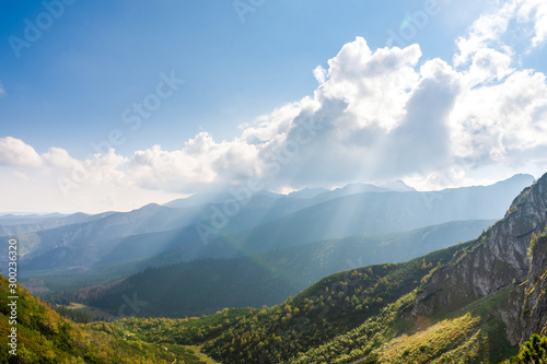 Mountain green vegetation and forests. Polish Tatras. The sun from behind the clouds. Place for text