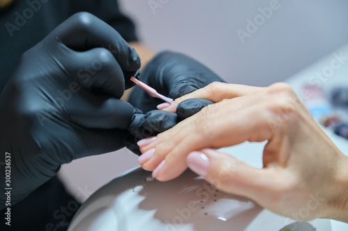 Manicurist varnishes gel nails. Professional hand and nail care in beauty salon