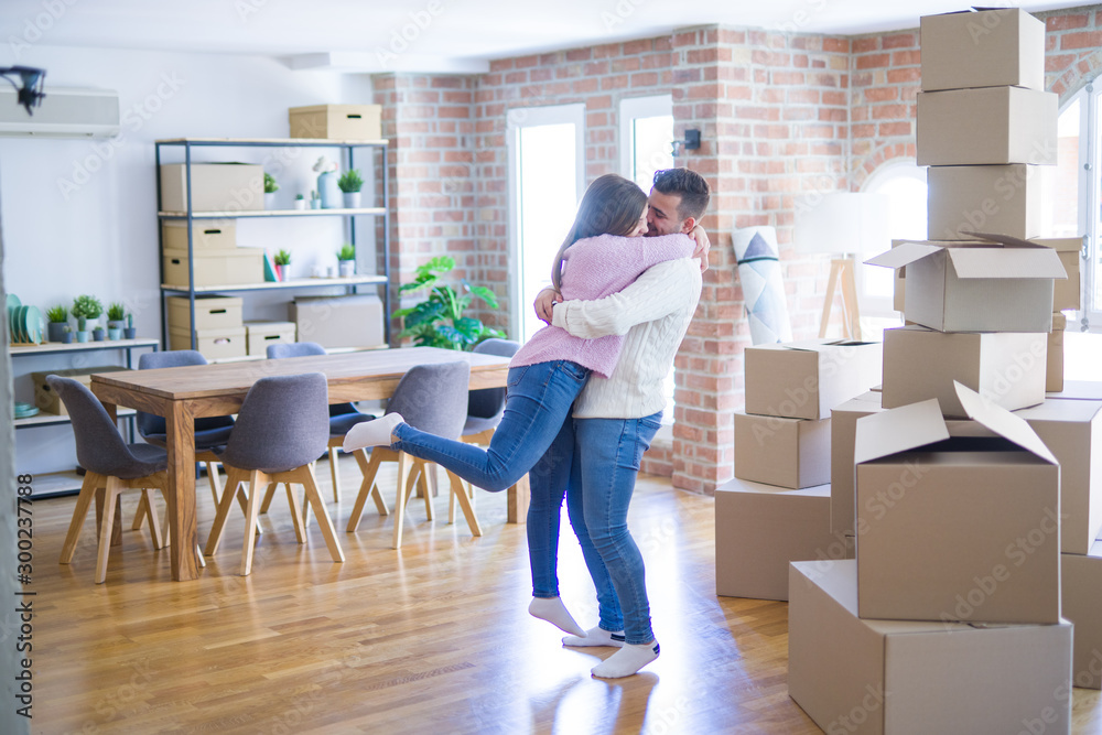 Young beautiful couple hugging in love celebrating very happy moving to new apartment Young beautiful couple hugging in love celebrating very happy moving to new apartment