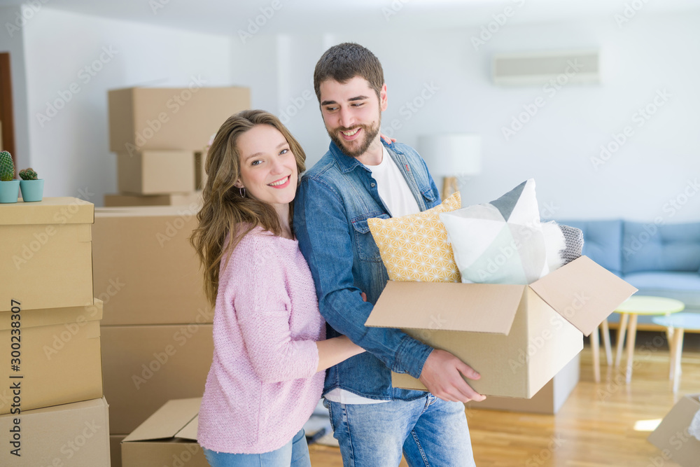 Young beautiful couple very happy together holding cardboard boxes moving to a new home