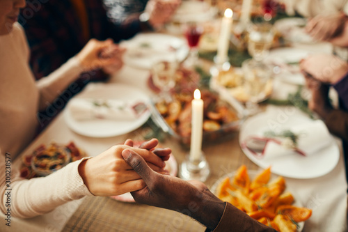 Canvas Print Closeup of people sitting at dining table on Christmas and joining hands in pray