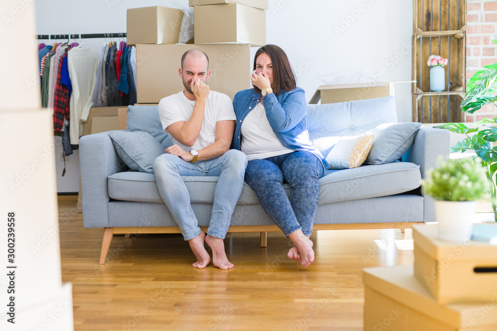 Young couple sitting on the sofa arround cardboard boxes moving to a