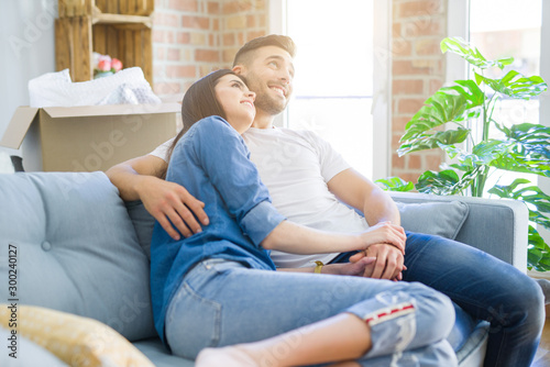 Beautiful couple hugging in love at the sofa, very happy smiling excited for new home