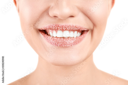 Young woman with sugar scrub on lips against white background  closeup
