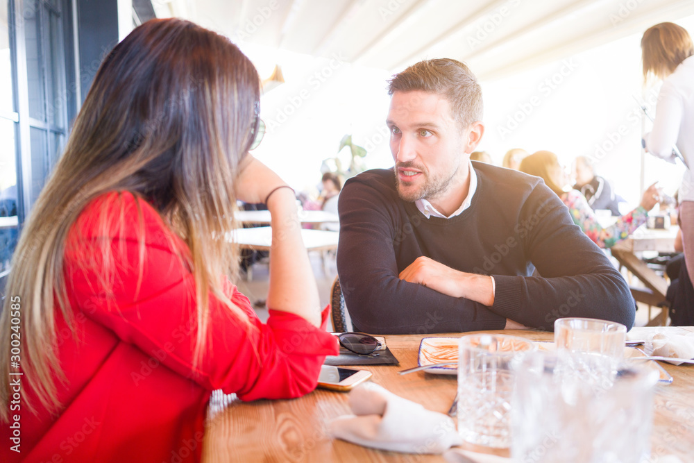 Obraz premium Young couple in love having a conversation at restaurante, talking happy and cheerful outdoors