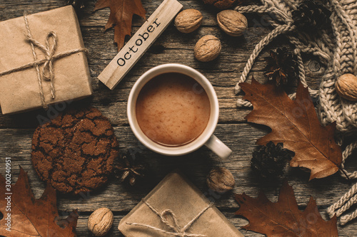 Cup of cocoa, cookies, nuts, dried autumn leaves on wood background. Autumn composition.