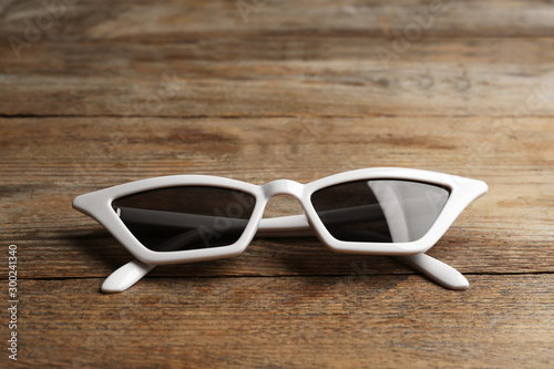 Stylish sunglasses on wooden background. Fashionable accessory
