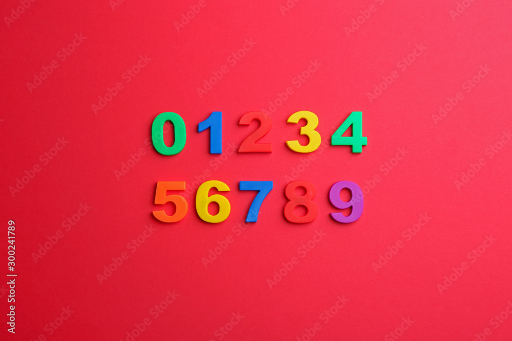 Colorful magnetic numbers on red background, flat lay Colorful magnetic numbers on red background, flat lay