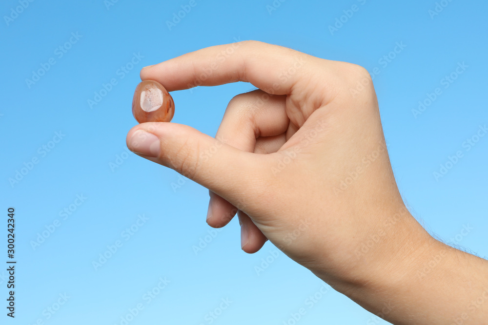 Woman holding agate gemstone against blue background, closeup Woman holding agate gemstone against blue background, closeup