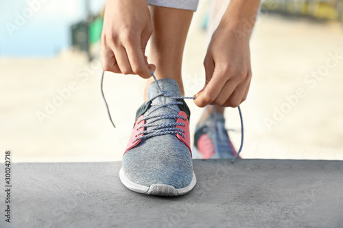 Sporty woman tying shoelaces before running outdoors