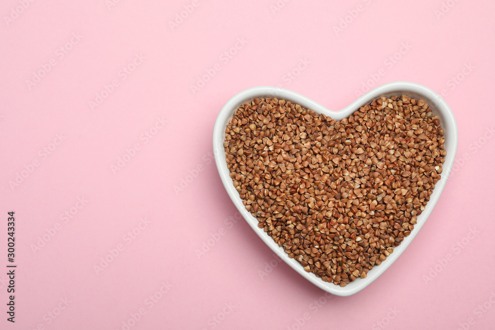 Buckwheat grains on pink background, top view. Space for text Buckwheat grains on pink background, top view. Space for text