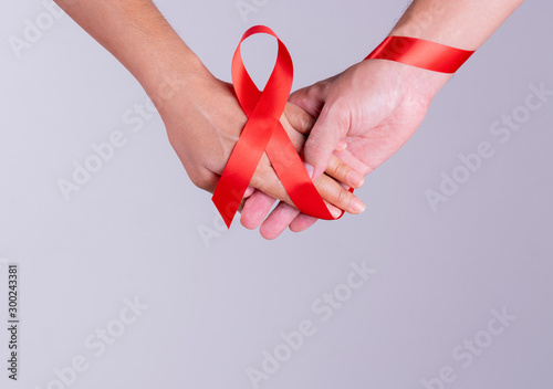 World AIDS Day. Holding hands with Red ribbon over grey background.