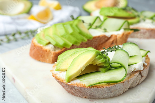 Tasty sandwiches with avocado and cucumber on table, closeup