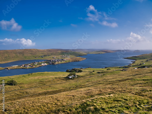 A view of Weisdale Voe on the west of Mainland, Shetland, Scotland, UK, taken on a sunny day with a blue sky and light clouds the houses at Kalliness and the Loch of Hellister appear on the left. photo