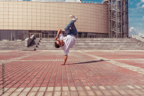 Modern male dancer, stand on one arm, dancing breakdance, in summer in city, free space text, hip-hop break dancer. Youth lifestyle, active, trendy, fitness sport, positive motivation.
