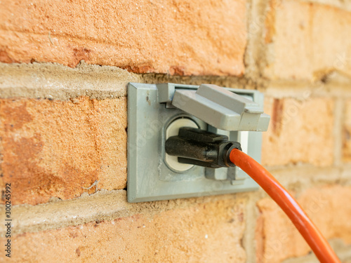 Schilderij op canvas Power cord plugged into outdoor electrical wall socket