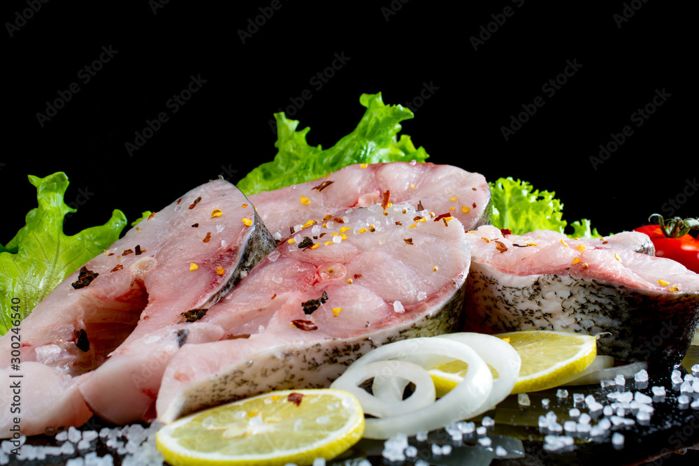 fish steaks with lettuce spices and tomatoes on a black background fish steaks with lettuce spices and tomatoes on a black background