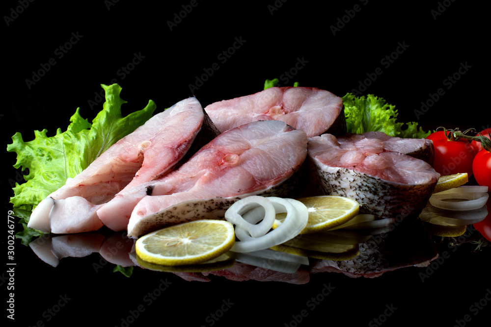 fish steaks with lettuce spices and tomatoes on a black background fish steaks with lettuce spices and tomatoes on a black background