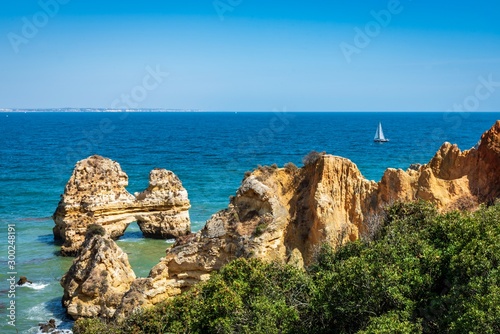 Boat sailing past the cliffs and sea stacks near Praia Dona Ana, Portugal. photo