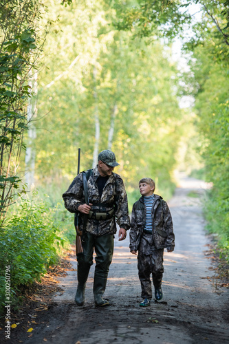 father pointing and guiding son on first deer hunt © romankosolapov