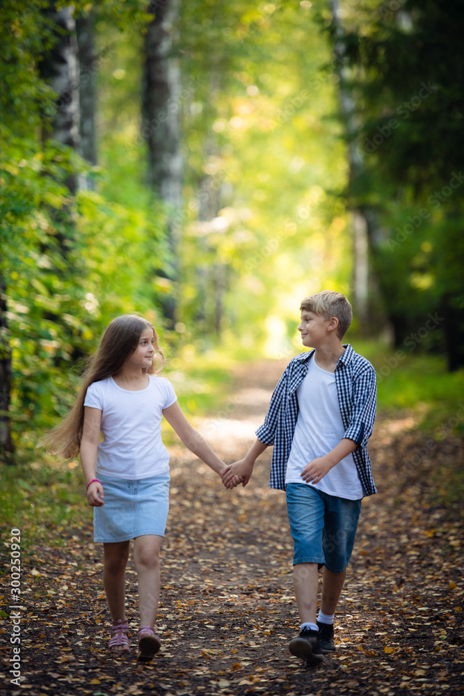First love. Little boy and girl holding hands and smiling while walking outdoors in park First love. Little boy and girl holding hands and smiling while walking outdoors in park