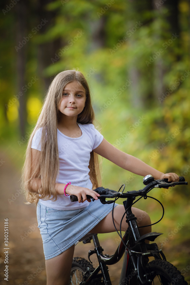 Cute little teenager girl riding bicycle in a sunny park Cute little teenager girl riding bicycle in a sunny park