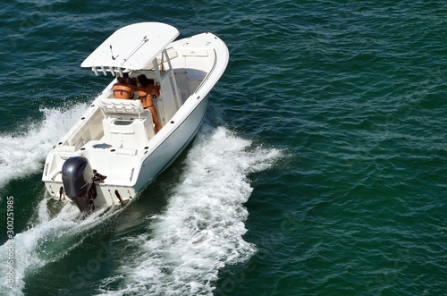 Angled overhead view of a young couple enjoying a week-end pleasure cruise in a small white sport fishing boat on the Florida Intra-Coastal Waterway.