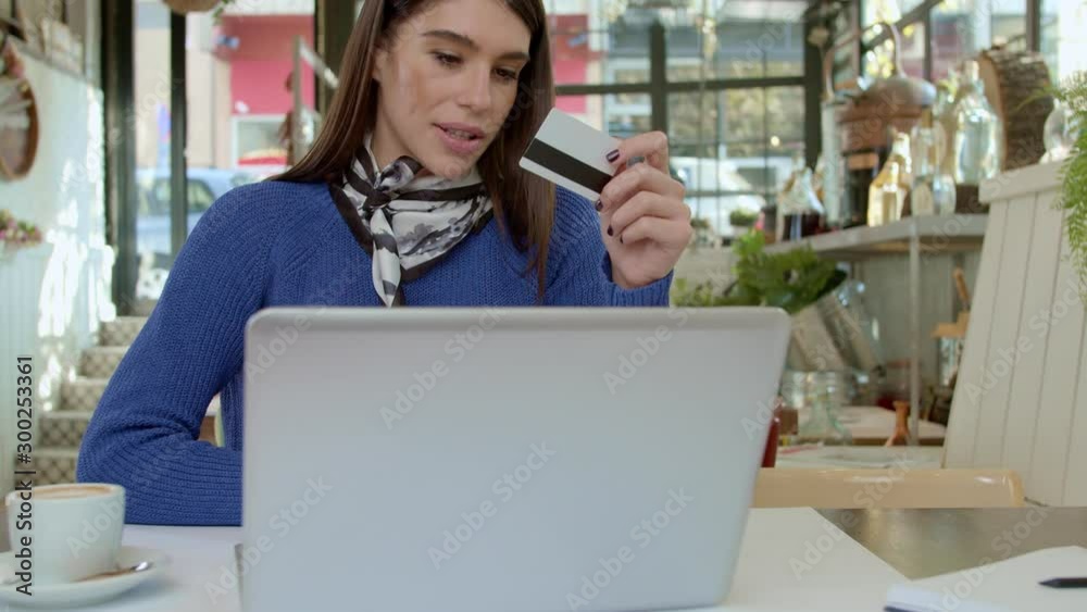 Gorgeous brunette sitting in cafe and using credit card for online shopping over laptop. Gorgeous brunette sitting in cafe and using credit card for online shopping over laptop.