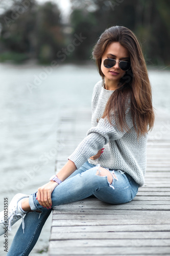Beautiful dreaming woman sitting on pier by the lake. © shootsroom