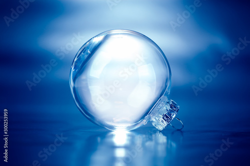Clear glass Christmas ornament on blue background with blank empty space