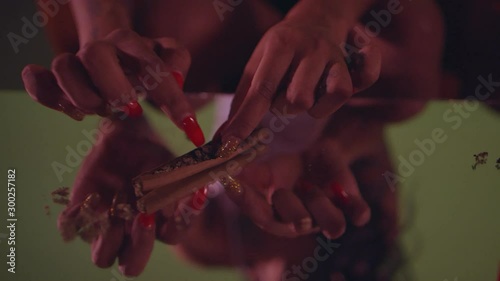 Close-up of a woman’s hands packing a marijuana joint photo