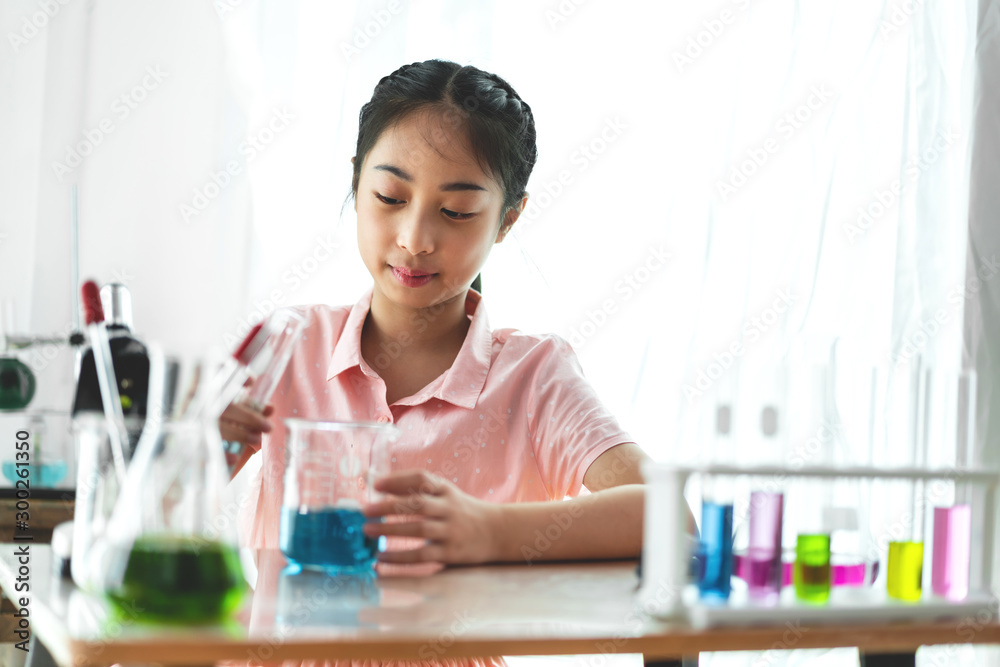 Teenage girl students learning and doing a chemical experiment and holding test tube in hands in science class on the table.Education concept Teenage girl students learning and doing a chemical experiment and holding test tube in hands in science class on the table.Education concept