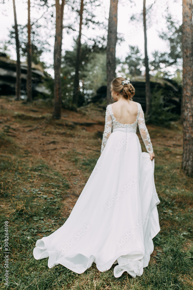 Elegant ceremony in European style. Beautiful bride in white flying dress in the forest.
