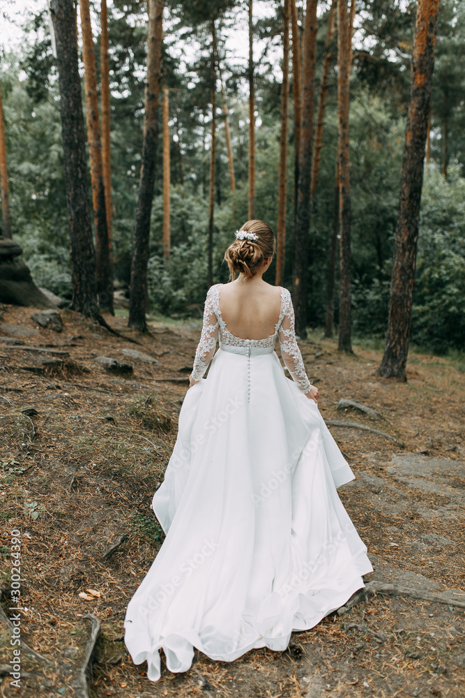 Elegant ceremony in European style. Beautiful bride in white flying dress in the forest.