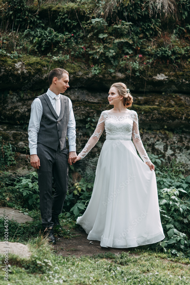 Modern ceremony in European style. Beautiful wedding couple in atmospheric forest with rocks.