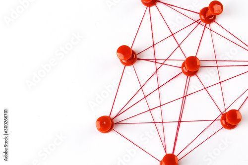 Network with red pins and string, linked together with string on a white background suggesting a network of connections.