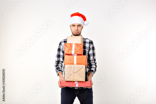 Holidays and presents concept - Funny man in Christmas Santa hat holding many gift boxes on white background